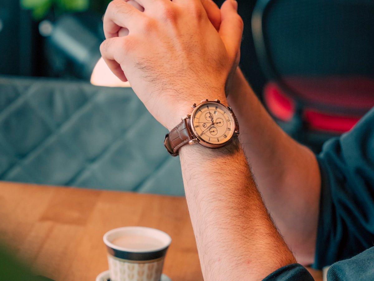 Manos de un hombre con reloj de piel sobre la mesa de una cafetería